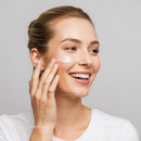 Young Woman Applying Skincare Cream with Bright Smile