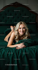 Smiling blonde woman relaxing on green velvet bed