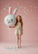 Young redhead girl holding bunny balloon with confetti