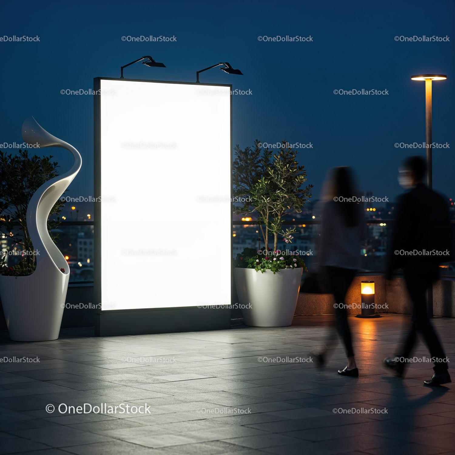 Para przechodzi nocą obok pustego, oświetlonego billboardu na zewnątrz