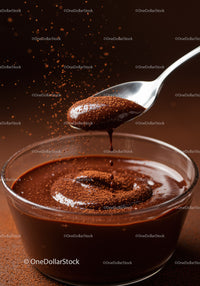 Rich chocolate sauce dripping from a spoon into bowl