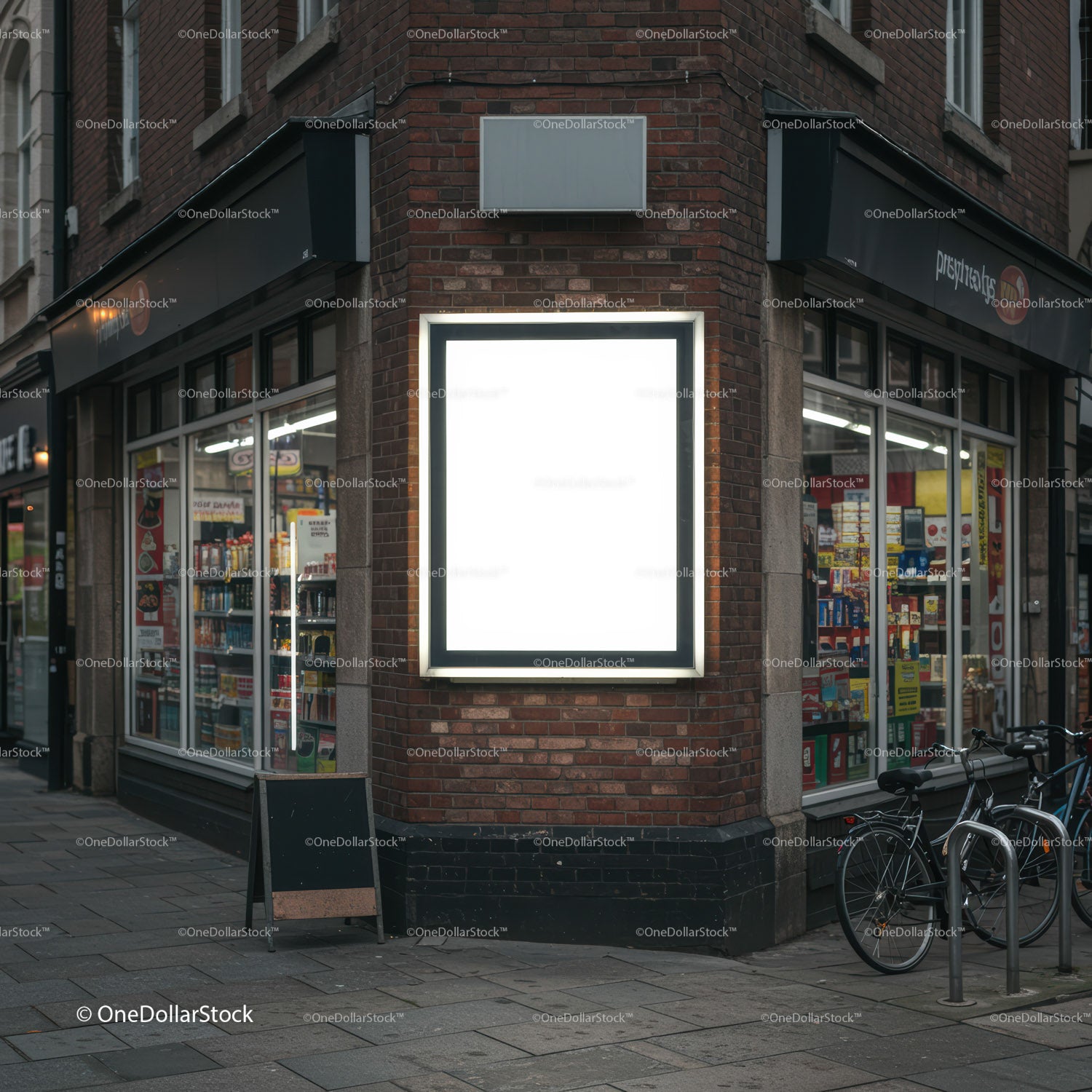 Blank illuminated billboard on urban store corner at dusk