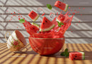 Fresh watermelon slices splashing in vibrant red bowl