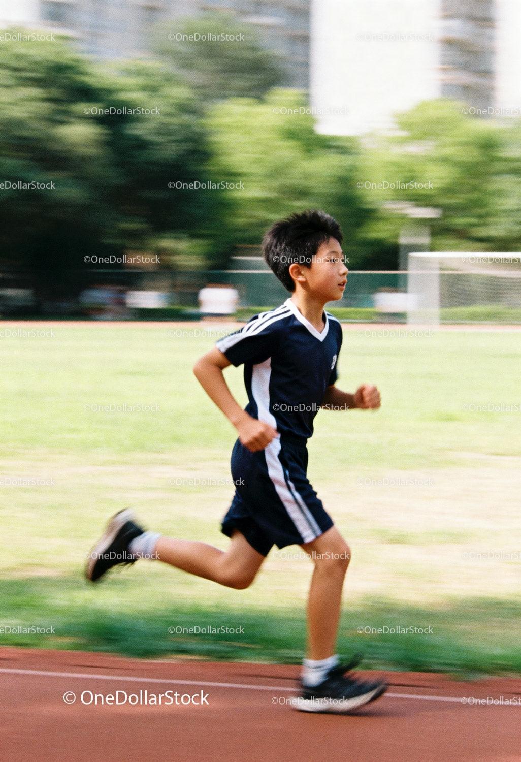 Young boy running energetically on outdoor track