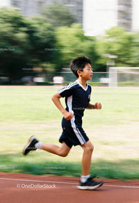 Young boy running energetically on outdoor track