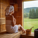 Relaxing woman in wooden sauna with scenic view of green landscape