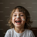 Happy child laughing with cream on face indoors