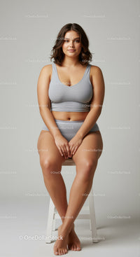 Confident Young Woman Sitting on Stool in Casual Grey Outfit