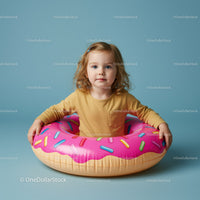 Toddler with inflatable donut pool float on blue background