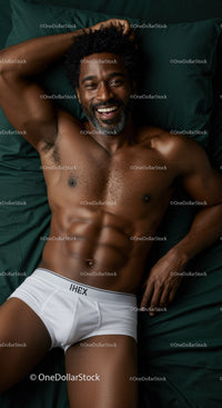 Smiling muscular man relaxing on dark green bedding