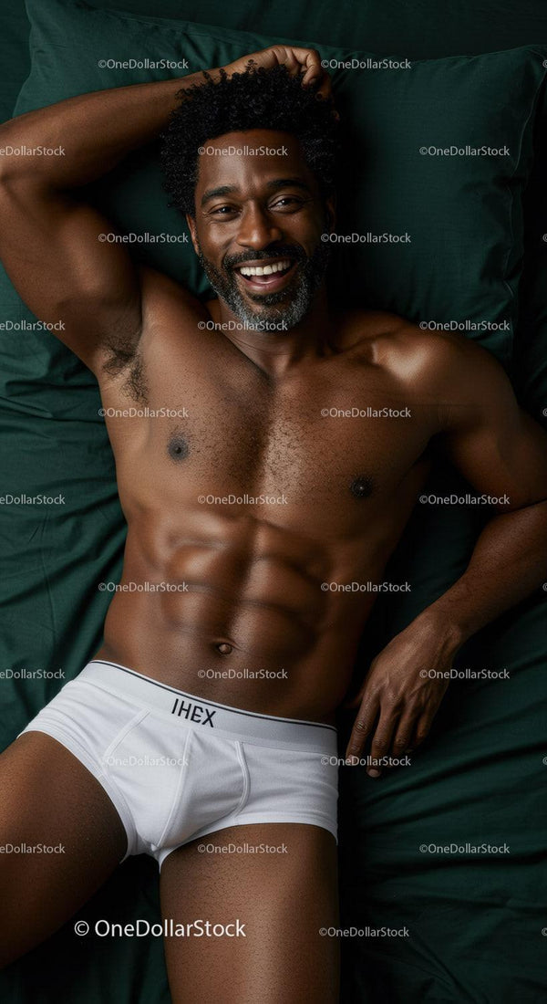 Smiling muscular man relaxing on dark green bedding