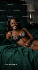 Smiling woman relaxing on dark green bed in elegant lingerie