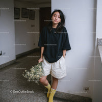Casual Young Woman Wearing Black T-Shirt and Yellow Socks Holding Daisies