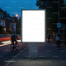 Empty illuminated billboard on urban street at dusk