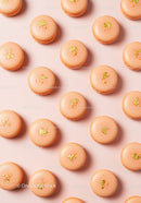 Elegant peach macarons with golden decoration on pink