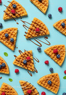 Waffle slices with berries and chocolate drizzle on blue