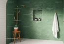 Modern green tiled shower with gold fixtures and plant
