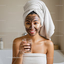 Young Woman Applying Facial Mask with Towel Wrap for Skin Care