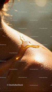 Golden honey drips down sunlit shoulder skin