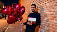 Man with heart balloons and chocolates on romantic evening