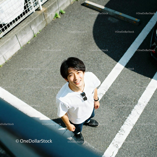 Young man smiling outdoors in sunny parking lot