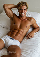 Smiling young man relaxing on bed in white underwear