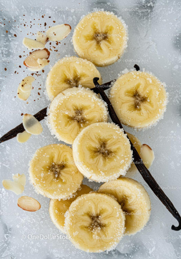Banana slices with sugar and vanilla on icy background