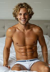 Smiling young man with curly hair sitting on bed
