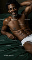 Smiling muscular man relaxing on bed in white underwear