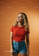 Young woman wearing red shirt looking thoughtfully upward