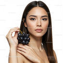 Elegant Woman Holding Black Grapes with Natural Beauty and Youthful Glow