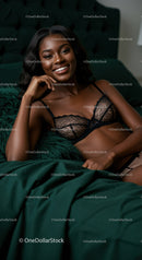 Smiling woman relaxing on dark green bed in lace lingerie