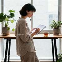 Focused woman writing notes beside bright window