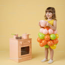 Little girl playing dress up with balloons and toy kitchen