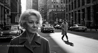Elderly Woman in Busy City Street Surrounded by Vintage Cars
