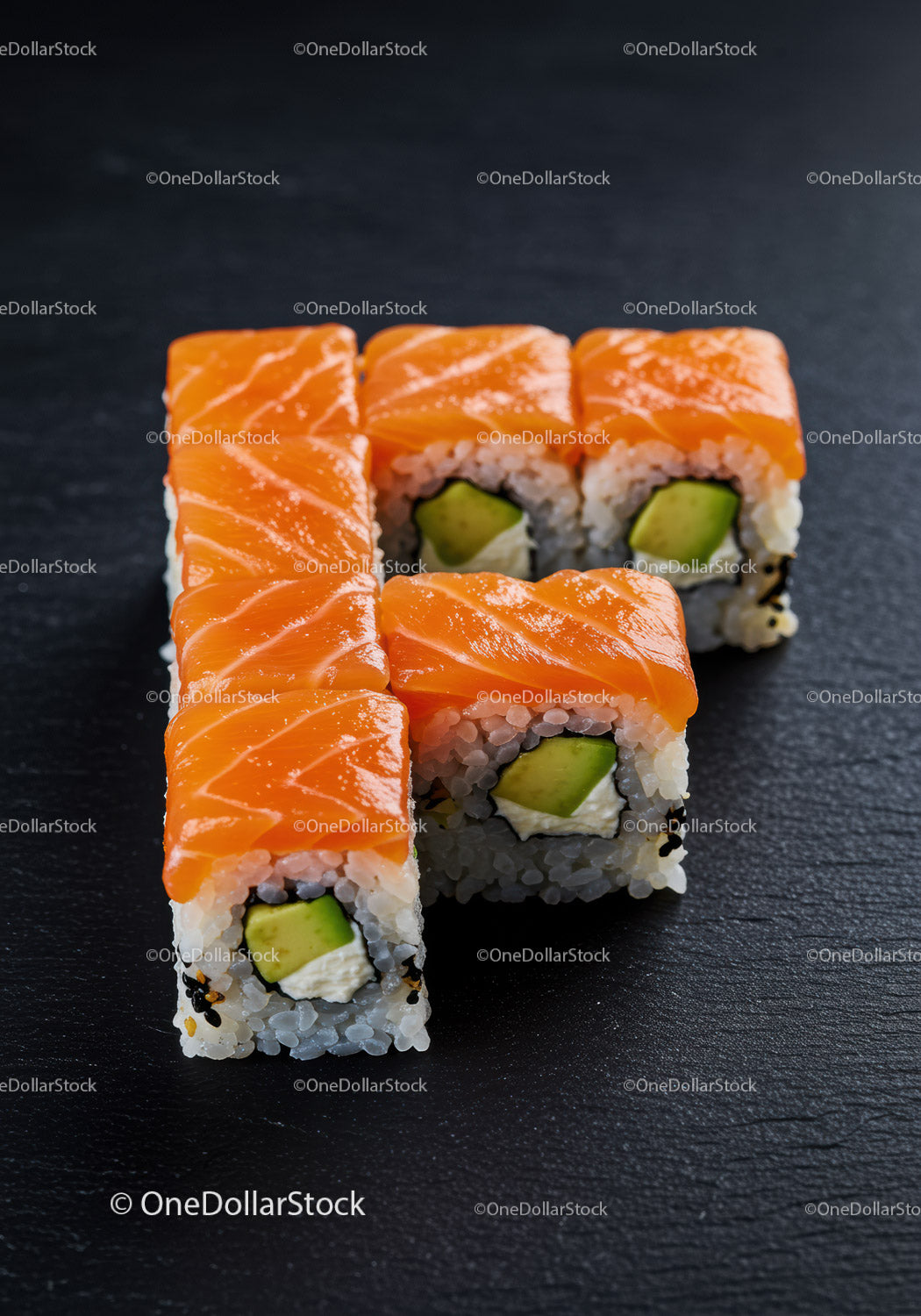 Fresh salmon avocado sushi rolls on black slate