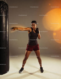 Focused woman boxing with punching bag in training studio