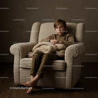 Thoughtful boy sitting barefoot on cozy armchair