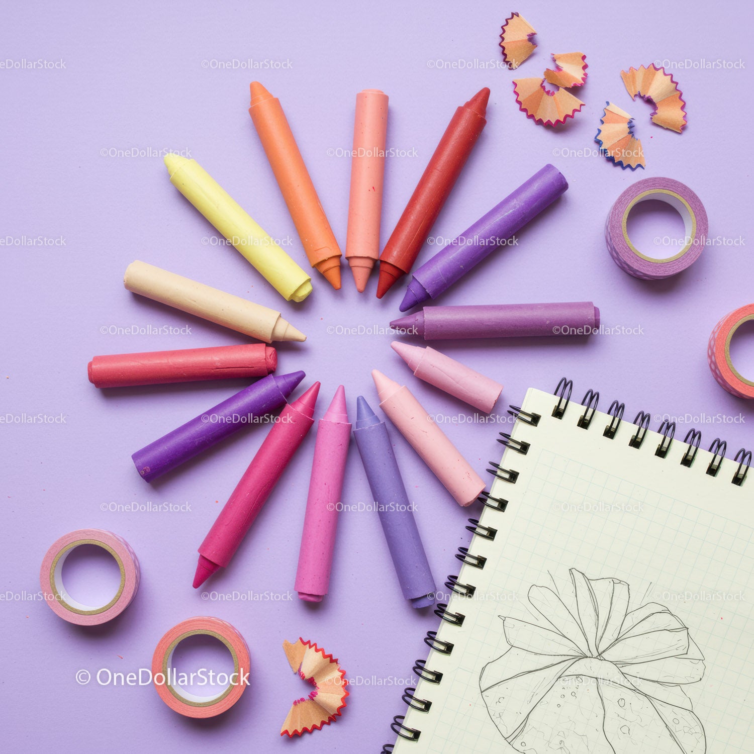 Colorful crayons arranged around sketchbook with drawing