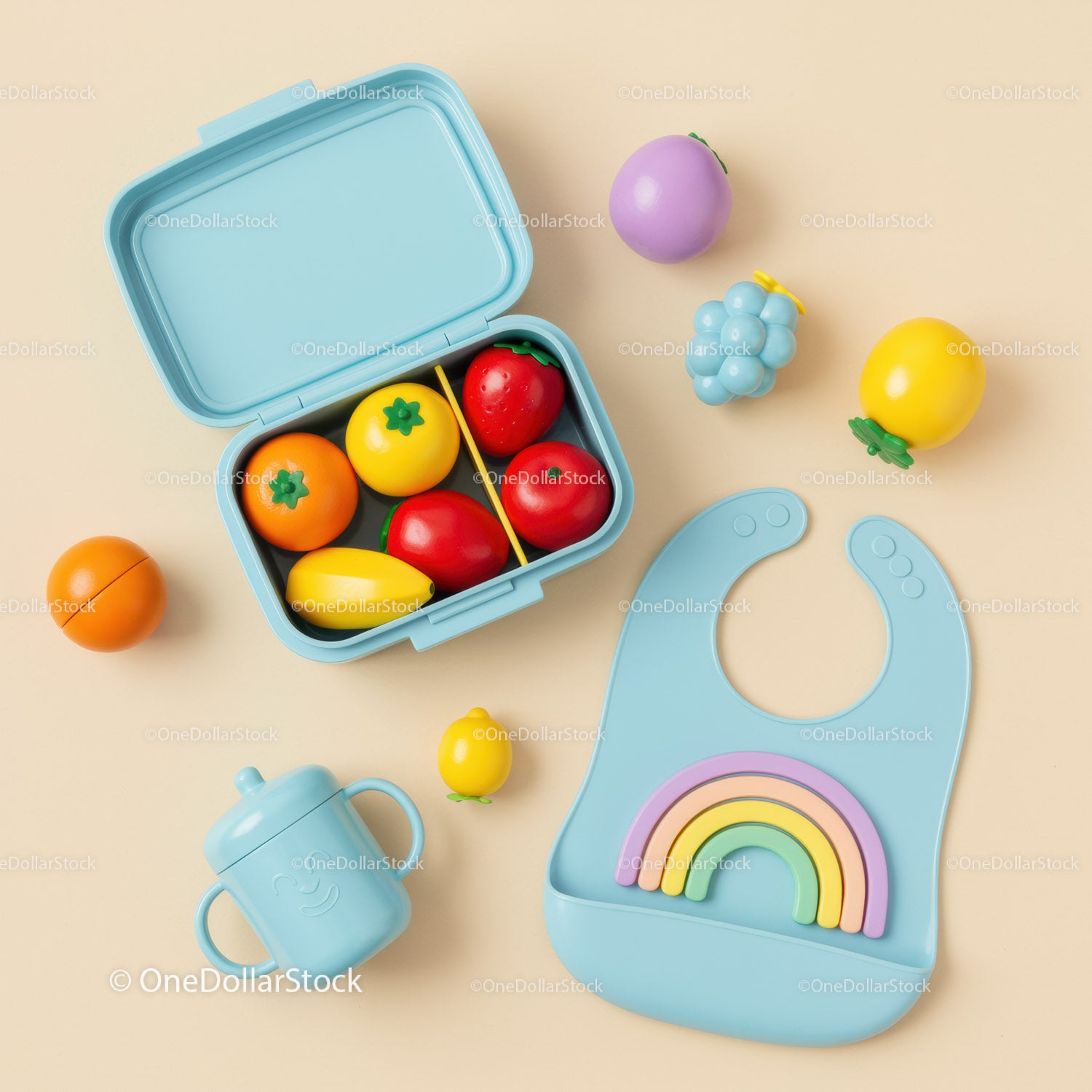Colorful baby feeding set with toy fruits on beige background