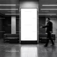 Blurred man walking past blank vertical billboard indoors