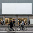 Busy urban street with pedestrians and cyclists passing shop
