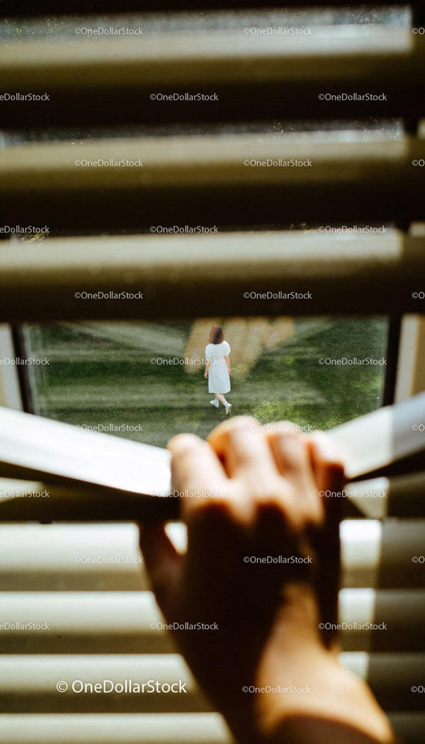 Hand peeking through blinds at woman walking outside