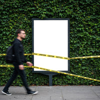 Man Walking Past Blank Poster with Caution Tape Outdoors