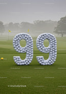Large Number 99 Made of Golf Balls on Green Lawn