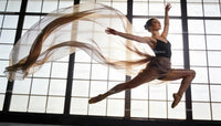 Graceful ballet dancer leaping midair with flowing scarf