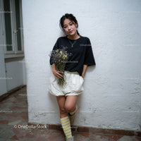 Casual Young Woman with Flowers Leaning Against White Wall