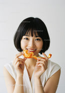 Joyful Woman Enjoying Fresh Tangerine in Bright Home Setting