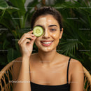 Woman Applying Clay Face Mask with Cucumber Slice Over Eye in Natural Setting