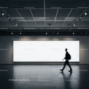 Silhouetted person walking by large illuminated billboard